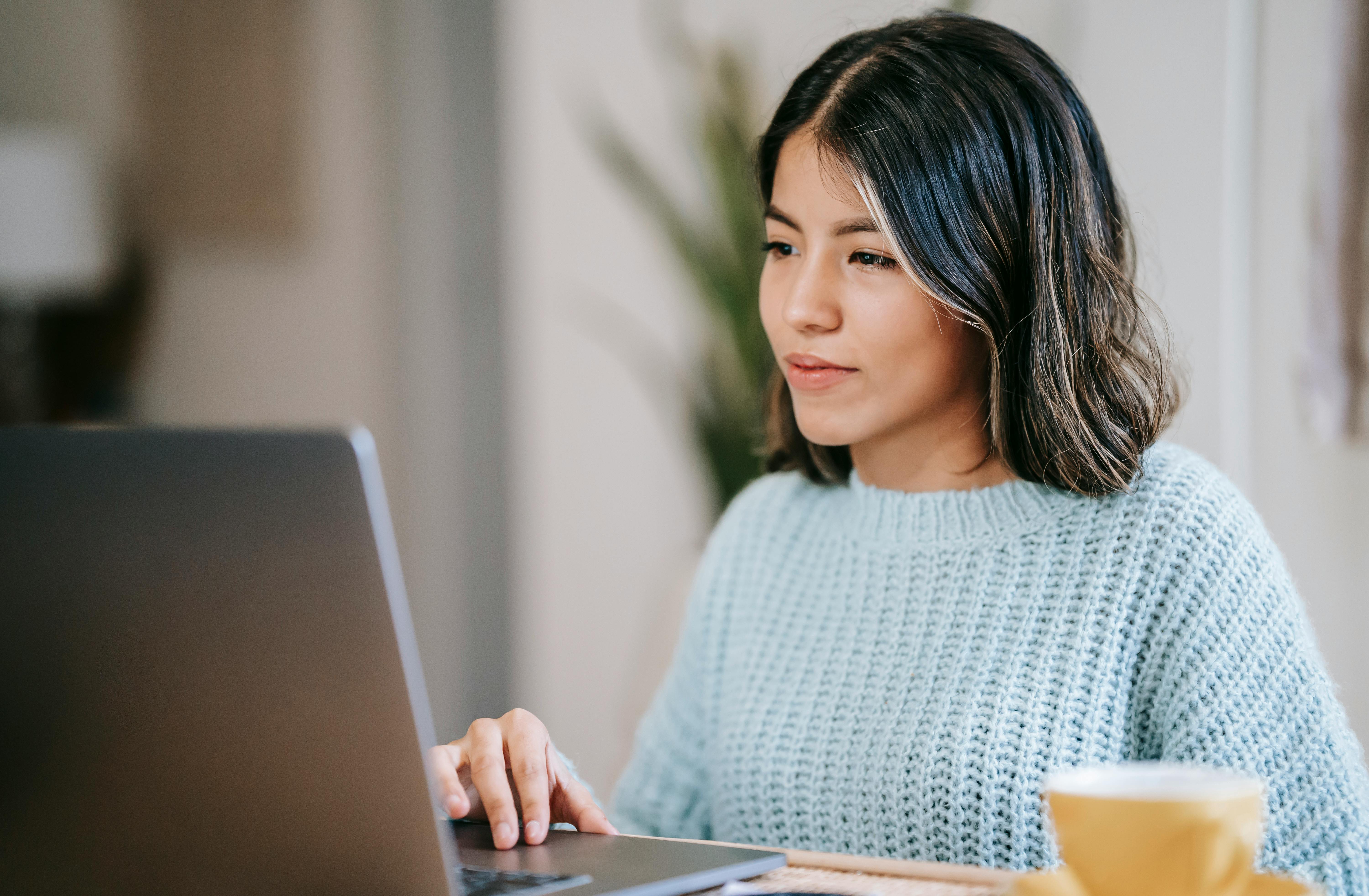 Frau Im Grauen Strickpullover Unter Verwendung Des Laptop Computers